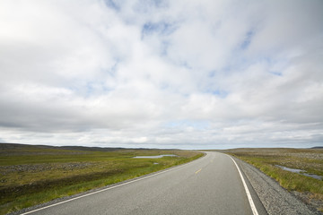 long highway in Norwegian tundra at autumn day