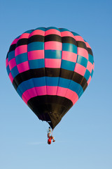 Fototapeta premium Colorful hot air balloon at festival mid-air on a clear day.