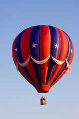 A Red White & Blue Hot Air Balloon on clear Day at Festival.