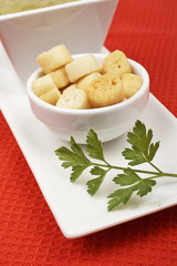 Bread croutons and parsley  on red mat. Shallow DOF