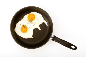 Two eggs in a black skillet frying pan on a white background