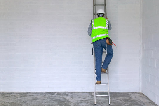 Workman in reflective vest and hard hat climbing a ladder - Powered by Adobe
