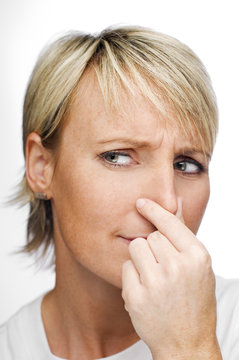 young blond woman holding her nose because of a bad smell