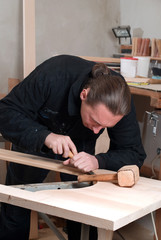 Young carpenter working in his workshop with hand tools