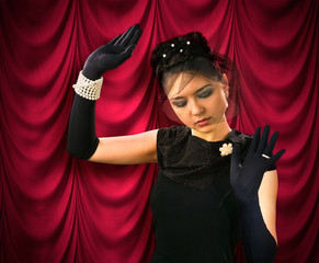 Theatrical actress on the background of red drapes