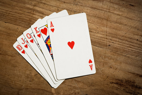 Royal flush poker hand on an old scratched table, copy space.