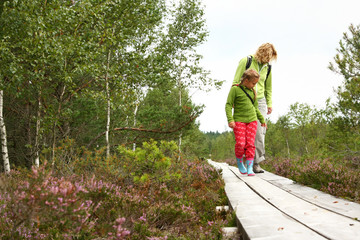 Mother and daughter walking on  plank-way in forest