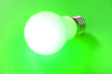 illuminated lightbulb on green background