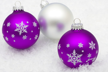 Fototapeta premium Purple and silver glass Christmas balls on snow background