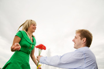 Young man present flowers to smiling woman