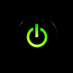 Glowing power button on black background