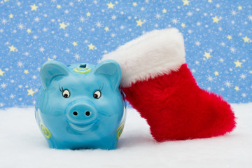 Piggy bank and red stocking sitting on snow, Christmas savings