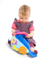 baby girl sitting on floor playing with stuffed animal toy.