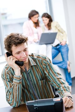 Young businessman receiving phone calls at office