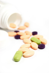 some colourful pills with bottle on a white background