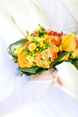 bouquet with yellow and orange roses in the hands of the bride