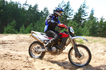 Man driving off-road motorbike in sand.