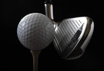 Golf club with ball on a tee in the black background