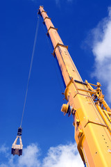 Yellow mobile crane hydraulic boom against blue sky © Marjan Paliuškevič