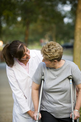 Naklejka premium physical therapist helping a woman on crutches