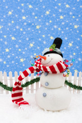Snowman and white picket fence with green garland and red bow