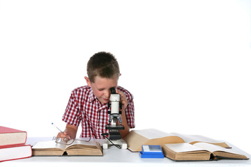 boy looking through a microscope and taking notes