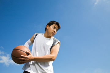 A shot of an asian basketball player holding a basketball