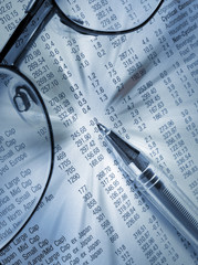 Close-up of pen and glasses on financial newspaper