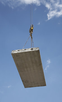 Hoisting crane lifts heavy concrete grey slab