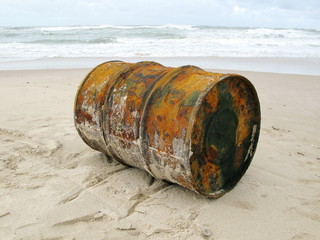 Bidon de pétrole rouillé échoué sur une plage.