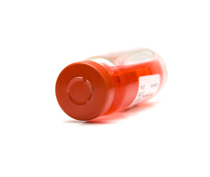 Transparent ampole with a red medicine on a white