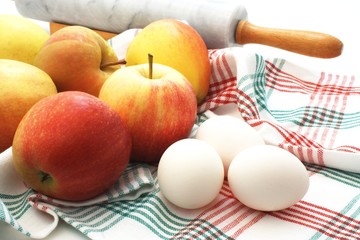 A couple of apple and eggs with a marble rolling pin.