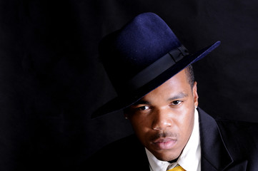 moody image of a young African American man in a hat