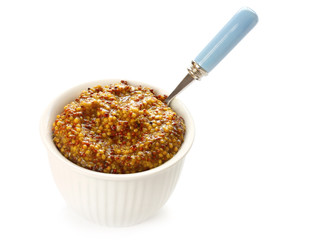 Bowl of seeded mustard, with spoon, on white background.