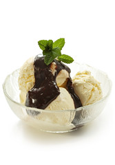 Bowl of vanilla icecream, topped with melted chocolate and mint.