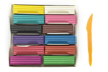 Color plasticine on a white background with a plastic knife