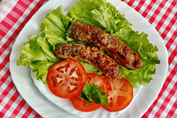 Grill sausage on leaves of salad with tomatoes