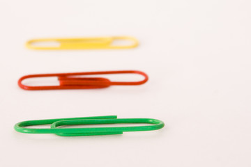 green red and yellow paper clips on white background