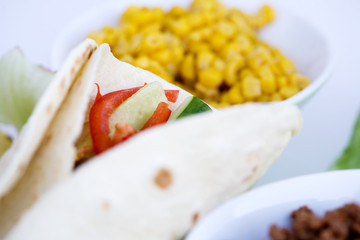 A macro of a prepared taco with ingredients in th background