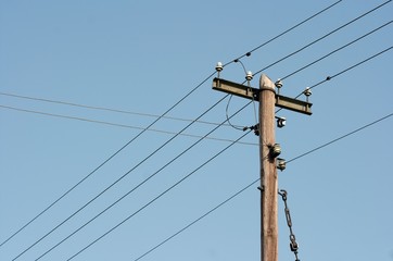 Old wooden electric pillar against clear blue sky