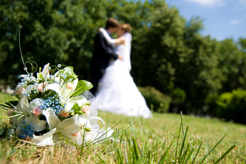 Bunch of white roses and newly-weds on a green background