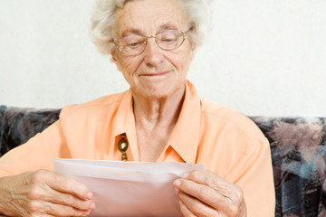 eine seniorin öffnet freudig einen briefumschlag - obrazy, fototapety, plakaty