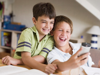 Two Young Boys Distracted From Homework, Playing With Cellphone