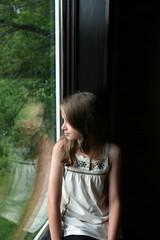 Obraz premium pretty girl looking out the window and sees her reflection