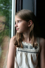Fototapeta premium pretty girl looking out the window and seeing her reflection