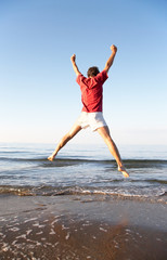 Back view of young man jumping on the beach