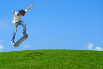 Young skater jumping over a green  hill.