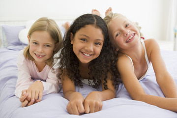 Three Young Girls Lying On A Bed In Their Pajamas