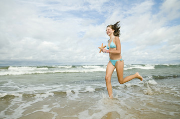 Beautiful young girl with starfish on the beach