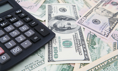 A Calculator over hundred and fifty US Dollars bills